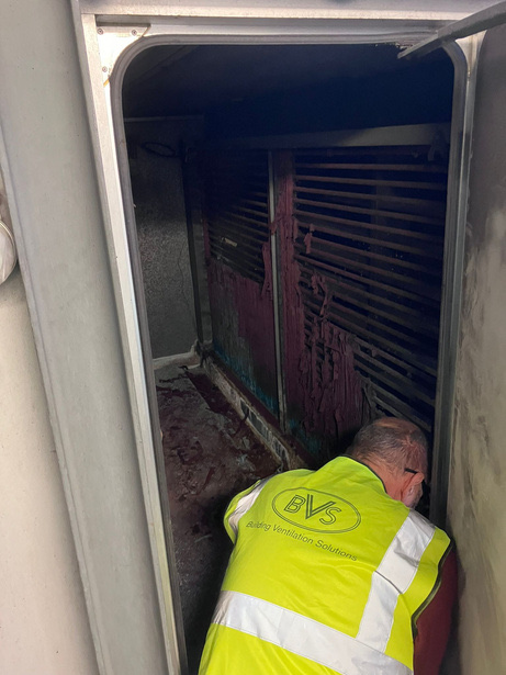 Engineer inspecting AHU interior during two-section coil installation at Burlington Street Office