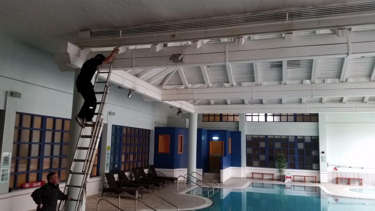 Engineer on ladder working on pool ceiling ductwork at Marriott Forest of Arden