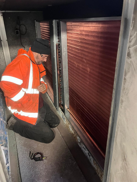 BVS engineer inspecting and replacing heating coil inside large AHU at pharmaceutical lab